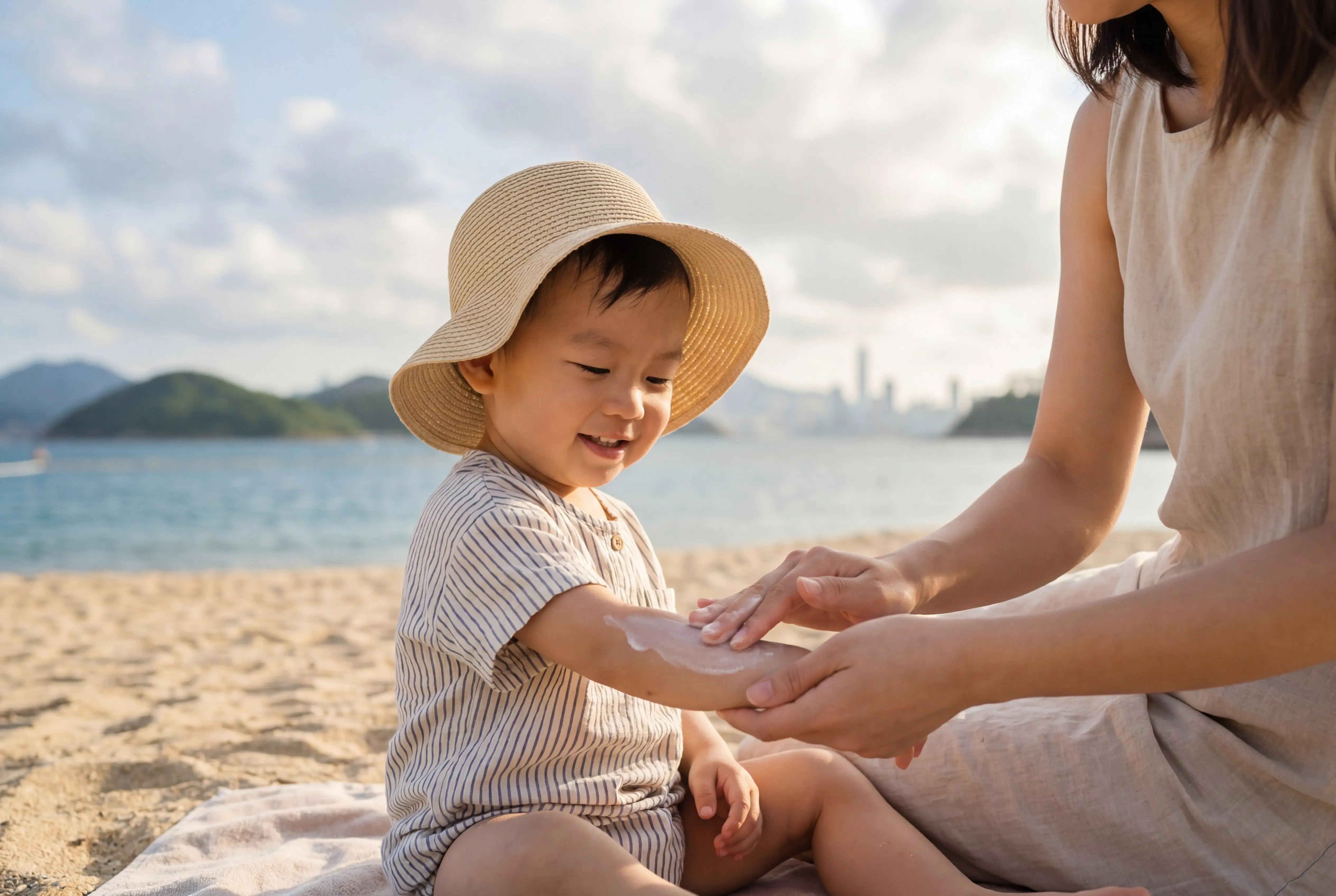 Baby Sunscreen Guide - Mother applying natural sunscreen to toddler at beach | BB兒童防曬指南